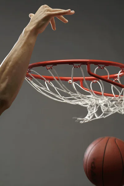 Ein Mann, der einen Basketball mit einer Hand durch ein Netz wirft — Stockfoto