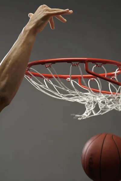 Ein Mann, der einen Basketball mit einer Hand durch ein Netz wirft — Stockfoto
