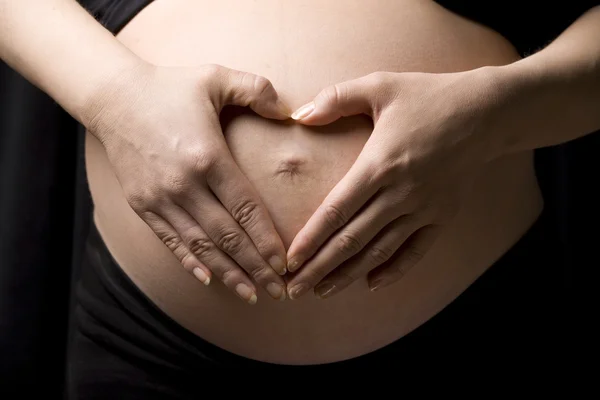 Een zwangere vrouw houden haar buik met beide handen — Stockfoto