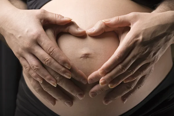 Kobieta w ciąży, trzymając jej brzuch z obiema rękami — Zdjęcie stockowe
