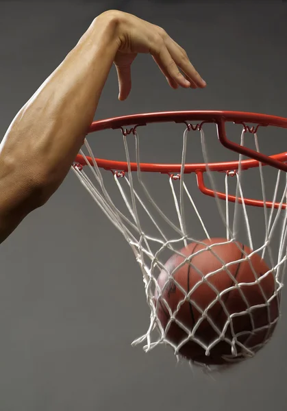 Um homem mergulhando uma bola de basquete através de uma rede com uma mão Fotos De Bancos De Imagens Sem Royalties