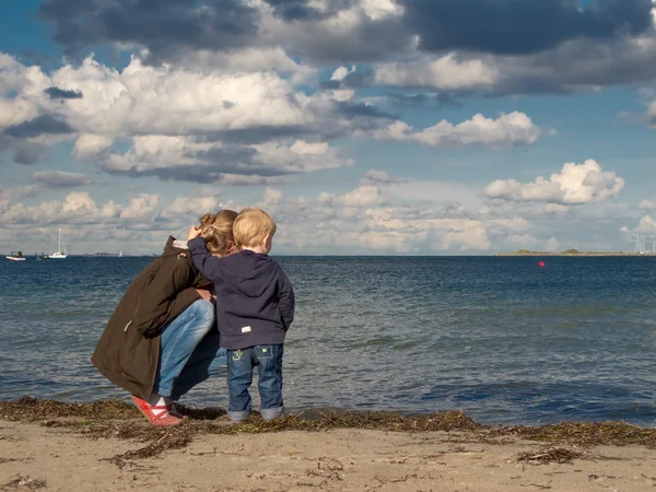 Мать и ребенок на пляже, смотрящем на море осенью — стоковое фото