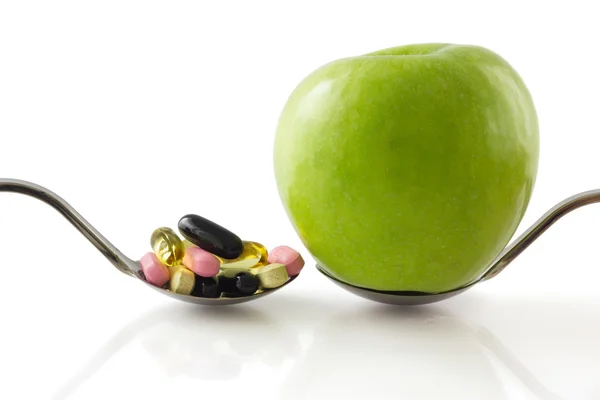 Cucchiaio con mela vs cucchiaio con pillole . — Foto Stock