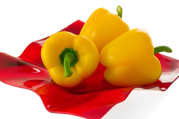 Yellow bell pepper on a red plate. — Stock Photo, Image