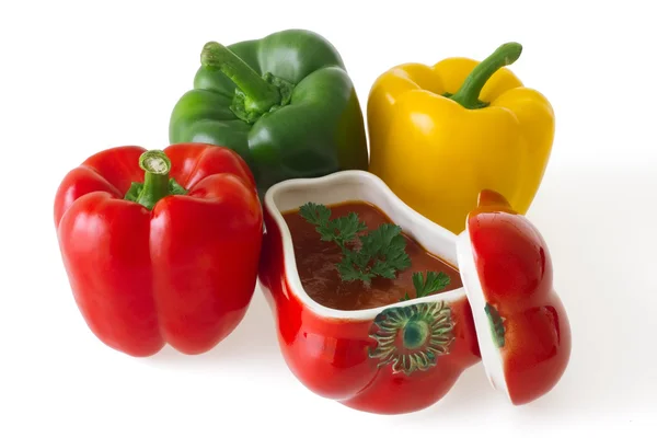 Red, green and yellow bell peppers with red ceramic ornament — Stock Photo, Image
