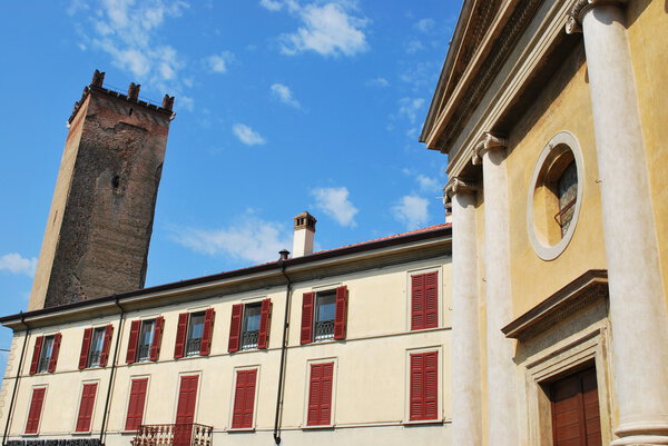 Yellow church facade and medieval tower in Castelleone, Cremona, Italy