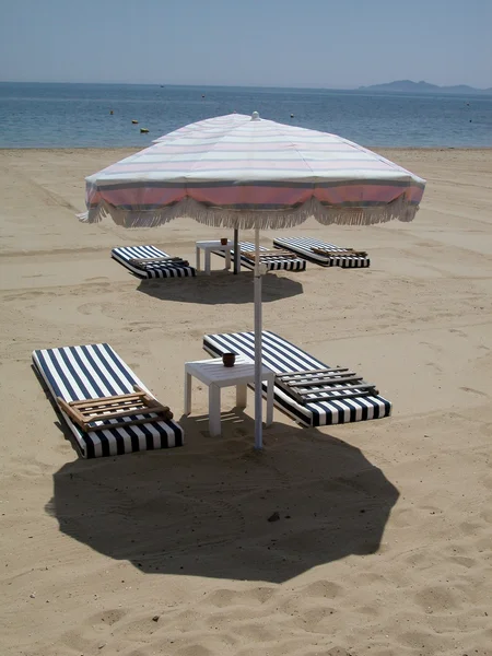 Зонтик и кровати на пляже — стоковое фото