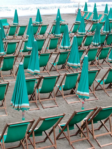 Espreguiçadeiras verdes e guarda-chuvas na praia — Fotografia de Stock
