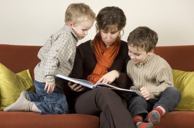 Mother And Two Sons Reading A Book 1 clipart