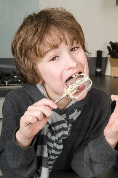 Jongen eten deeg van een klopper — Stockfoto
