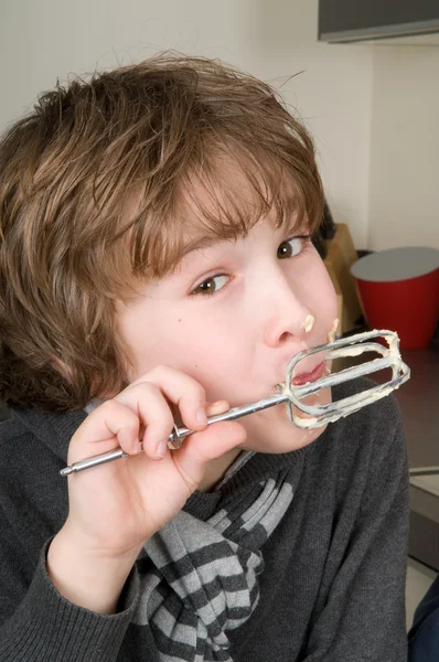 Pojken äta degen från en visp — Stockfoto