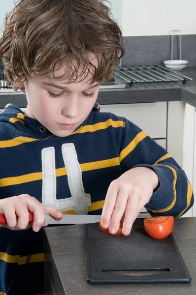 Junge schneidet Tomate — Stockfoto