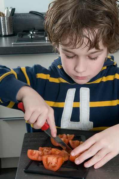 Мальчик режет помидоры — стоковое фото