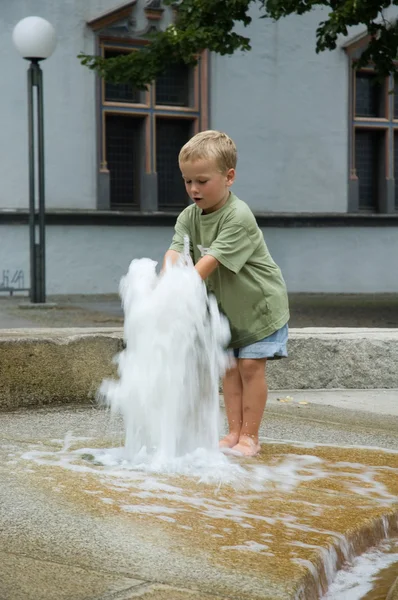 Junge spielt mit Springbrunnen — Stockfoto