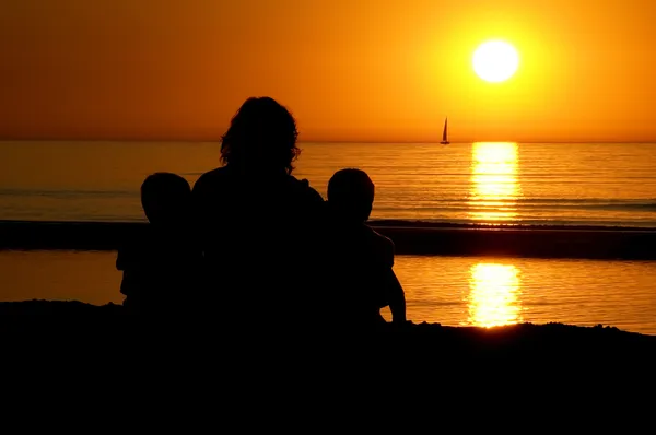 Rodzina siedzi przy zachodzie słońca — Zdjęcie stockowe