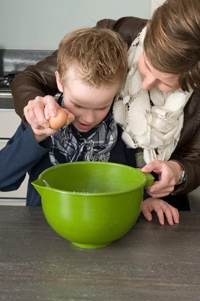 Мальчик и мать делают тесто для тортов — стоковое фото