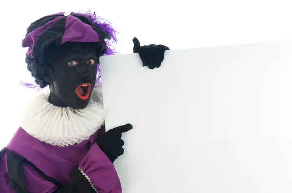 Zwarte Piet looking at a white board, to put your text in. — Stock Photo, Image