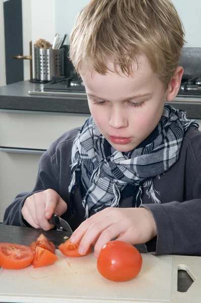 Jongen snijden tomaat — Stockfoto