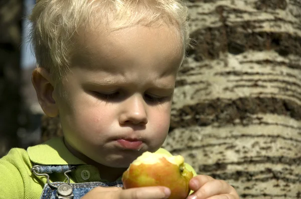 Liten pojke med saftigt äpple — Stockfoto
