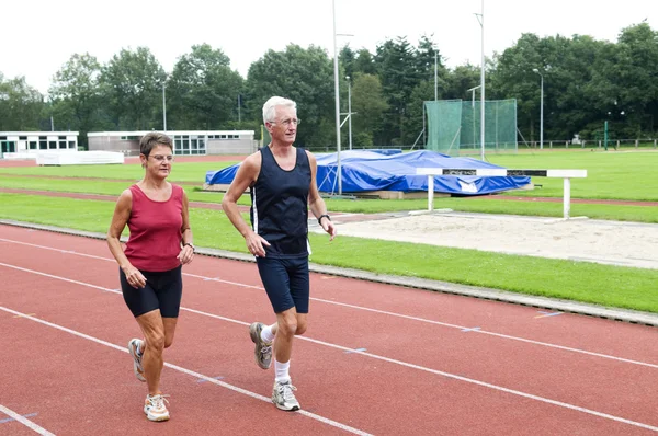 Senior Couple Running On A Track — Stock Photo, Image