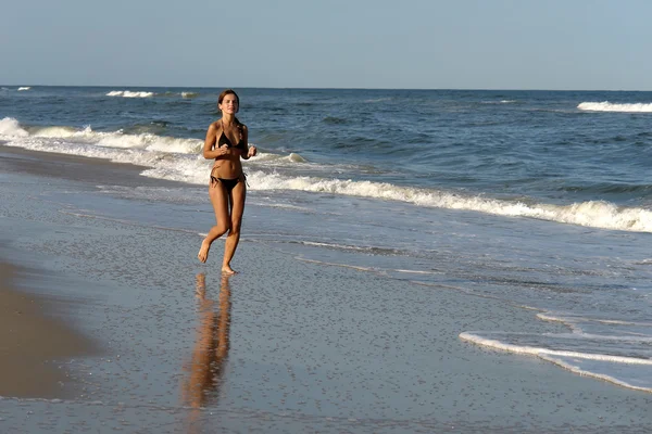 Mladá žena běží na pláži — Stock fotografie