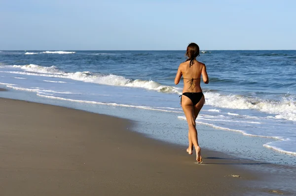 Mladá žena běží na pláži — Stock fotografie