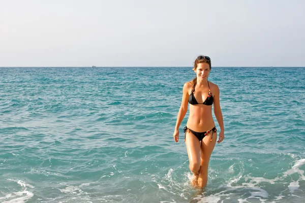 Kumsalda yürüyen güzel genç bir kadın. — Stok fotoğraf