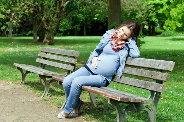 Kobieta w ciąży siedząc na ławce — Zdjęcie stockowe