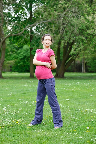 Těhotná žena cvičení v parku — Stock fotografie