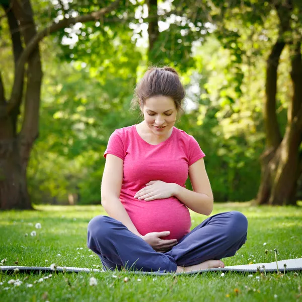 Gravid kvinna avkopplande i parken — Stockfoto