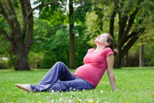 Mujer embarazada relajándose en el parque Imagen De Stock