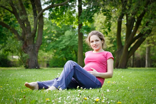 怀孕的女人放松在公园 免版税图库图片