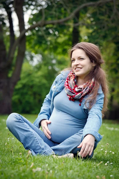 Pregnant woman relaxing in the park Stock Image