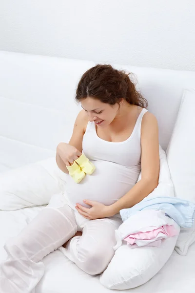 Красивая беременная женщина выбирает одежду для ребенка — стоковое фото