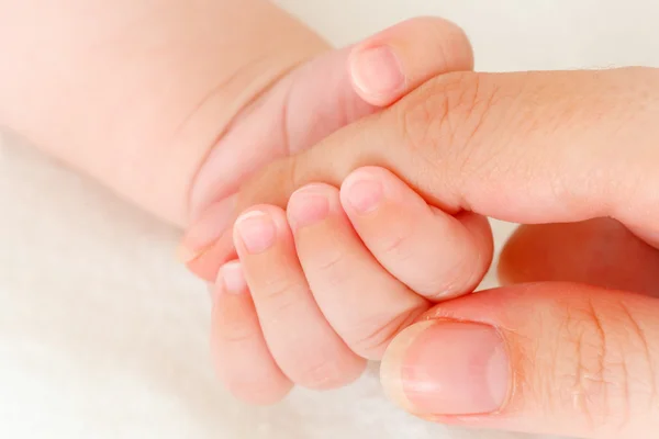 Közelkép a baba kezéről, ahogy az anya ujját fogja. — Stock Fotó
