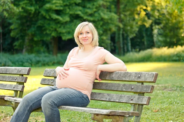Těhotná žena odpočívající v parku — Stock fotografie