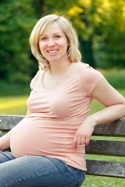 妊娠中の女性が公園で休んでいる — ストック写真