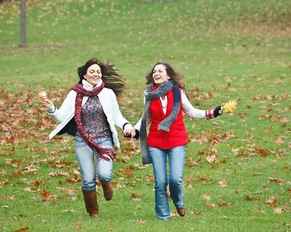 Две симпатичные девушки веселятся в осеннем парке — стоковое фото
