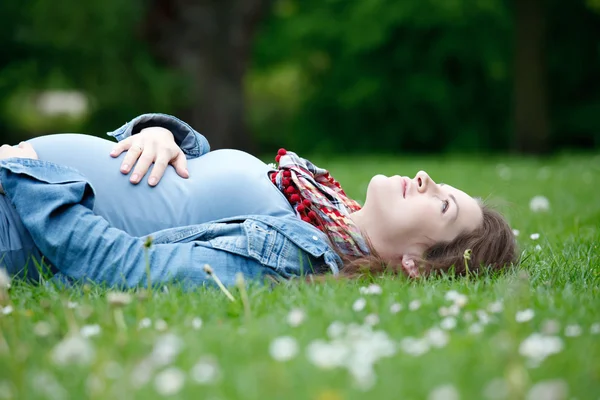 Mooie zwangere vrouw ontspannen op gras — Stockfoto