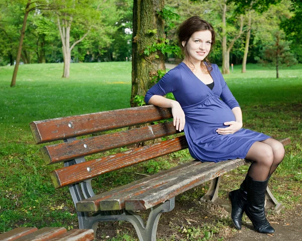 Mulher grávida bonita sentada no banco — Fotografia de Stock