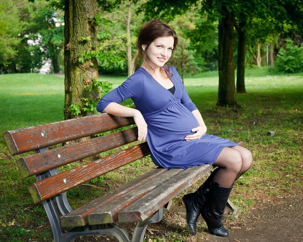 Красивая беременная женщина сидит на скамейке — стоковое фото