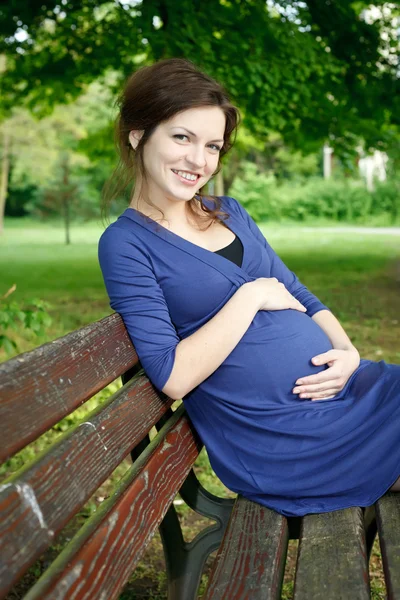 Piękna kobieta w ciąży, siedząc na ławce — Zdjęcie stockowe