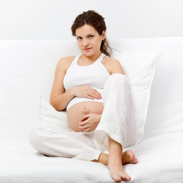 Genç hamile kadın kanepede oturuyor. — Stok fotoğraf