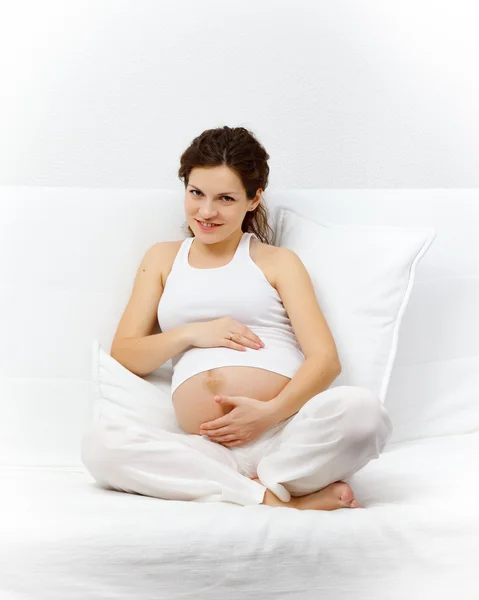 Mladá těhotná žena uvolňující na pohovce — Stock fotografie