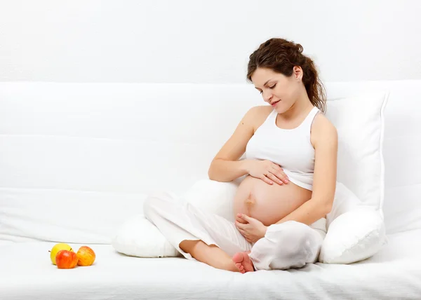 Młoda kobieta w ciąży na kanapie — Zdjęcie stockowe