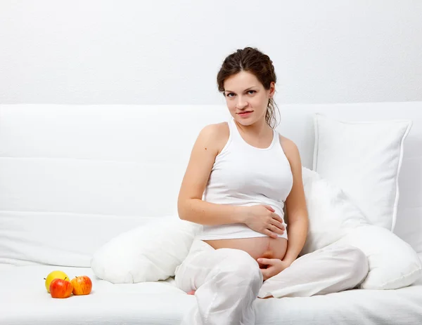 Mujer embarazada joven sentada en el sofá — Foto de Stock