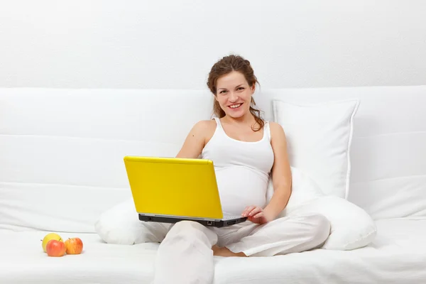 Jeune femme enceinte avec un ordinateur portable — Photo