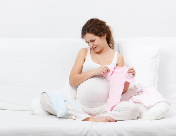 Mulher grávida bonita escolhendo roupas de bebê — Fotografia de Stock