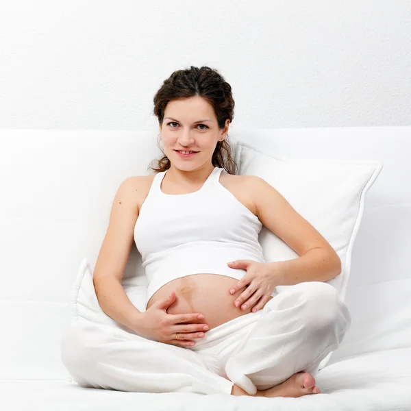 Unga gravid kvinna avkopplande på soffa Stockbild