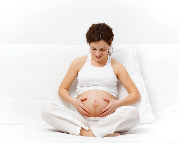 Unga gravid kvinna avkopplande på soffa Stockbild